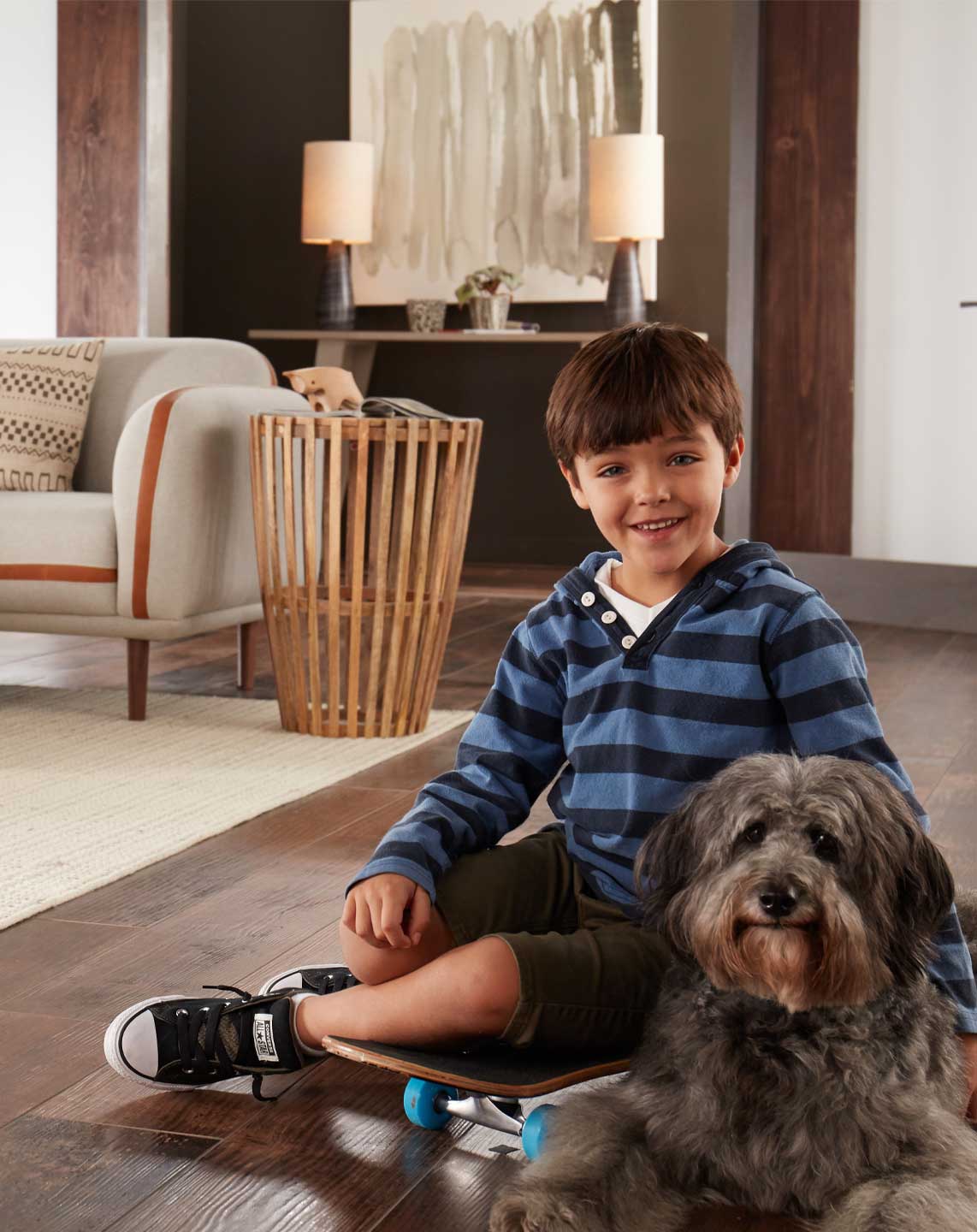 boy and dog sitting on hardwood floor